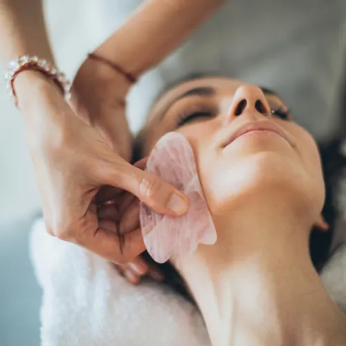 Massaggio viso Gua Sha con pietra di quarzo rosa